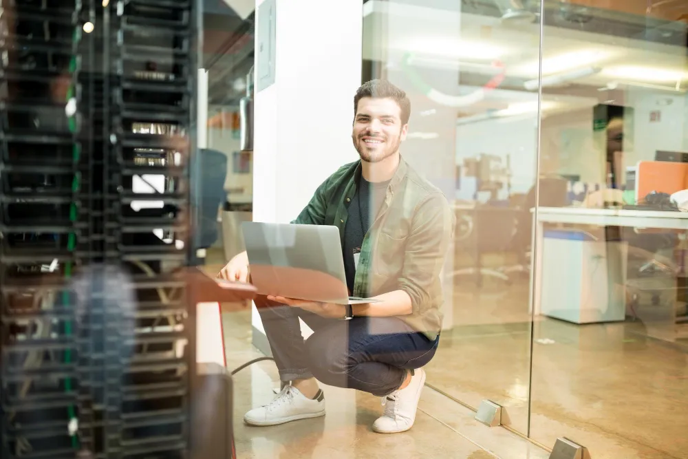 person sitting with a laptop in server room